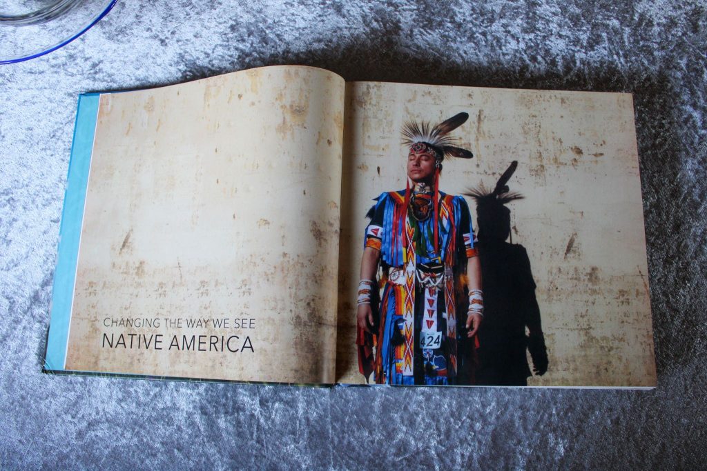 Foto vom aufgeschlagenen Buch, trifft auch auf alle folgenden Fotos zu.
Links steht in großer Schrift: "Changing  the way we see Native America".
Rechts ein junger indigener Mann in  bunter traditioneller Kleidung mit Federschmuck.