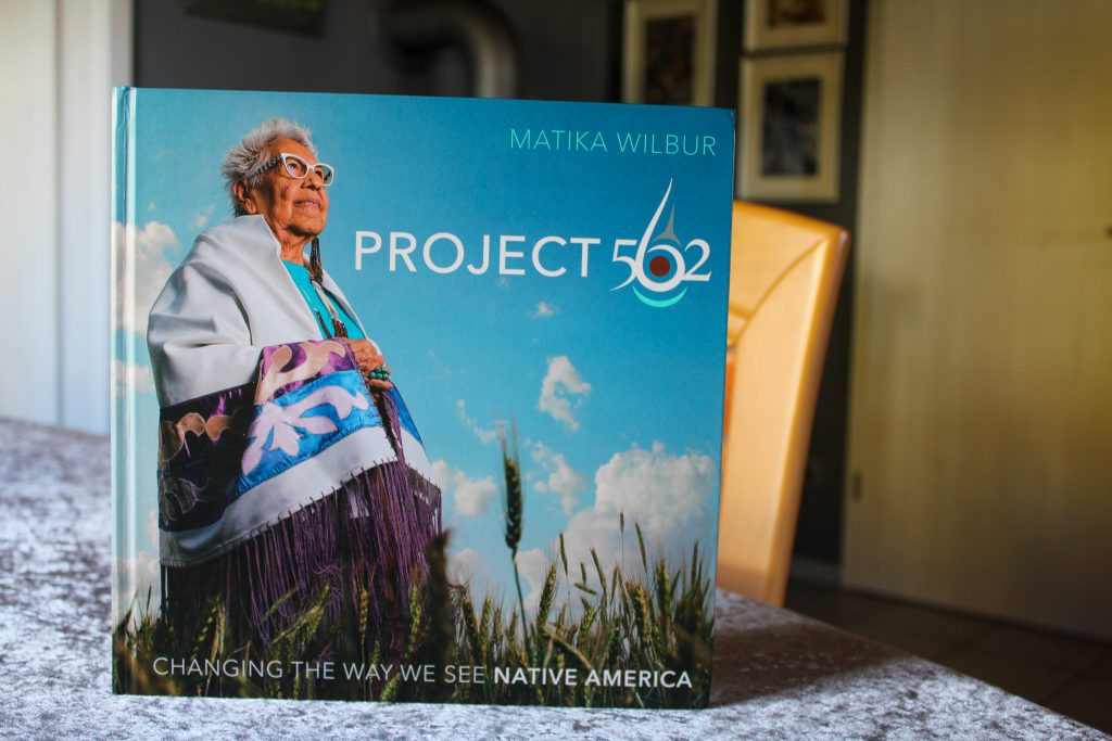 Cover des Buchs "Project 562", das eine ältere indigene Frau in traditioneller Kleidung auf einem Weizenfeld vor blauem Himmel zeigt
